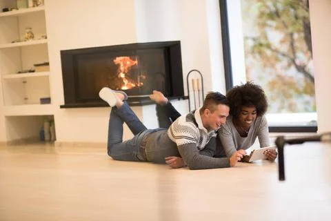 Multiethnic couple using tablet computer on the floor beautiful young mult... Stock Photos