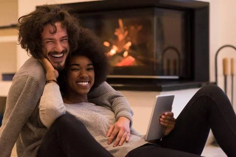 Multiethnic couple using tablet computer on the floor beautiful young mult... Stock Photos