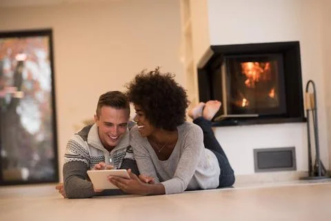 Multiethnic couple using tablet computer on the floor beautiful young mult... Stock Photos
