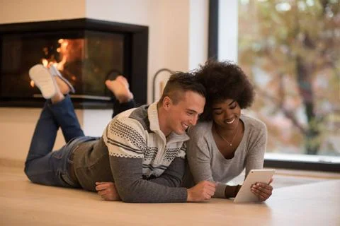 Multiethnic couple using tablet computer on the floor beautiful young mult... Stock Photos