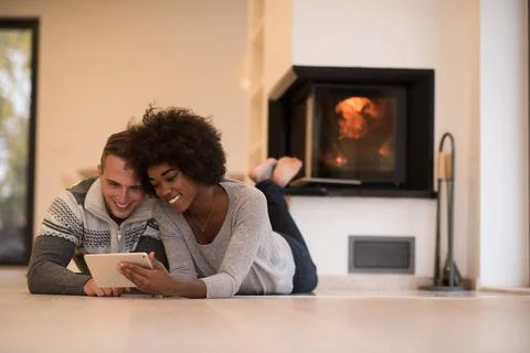 Multiethnic couple using tablet computer on the floor beautiful young mult... Stock Photos