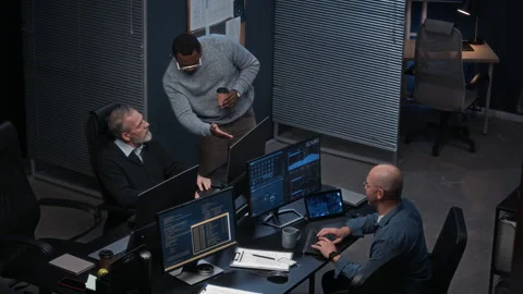 Multiethnic Cybersecurity Workers Interacting at Desk with Multiple Screens Stock Footage 324052295