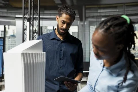 Multiethnic developers reviewing 3D models details to create a layout Stock Photos