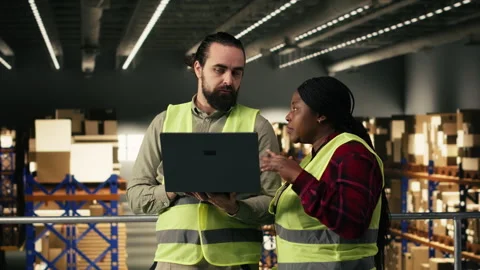 Multiethnic employees managing warehouse operations on laptop software Stock Footage 330207561