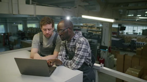 Multiethnic Engineers Discussing Data on Laptop in Printing Center Warehouse 스톡 동영상 335486687