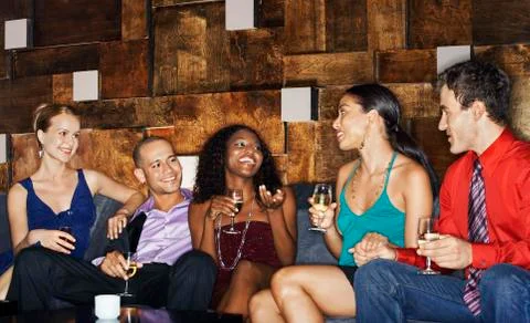 Multiethnic Friends On Couch With Drinks Stock Photos