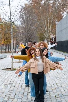 Multiethnic friends smiling while posing standing in a row with their arms open. Fotos de archivo