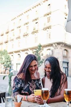 Multiethnic friends using the mobile in a bar terrace Stock Photos