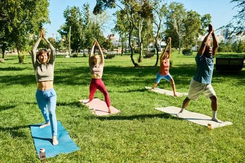 Multiethnic Group of Adults Practicing Yoga Outdoors in Green Park Foto stock