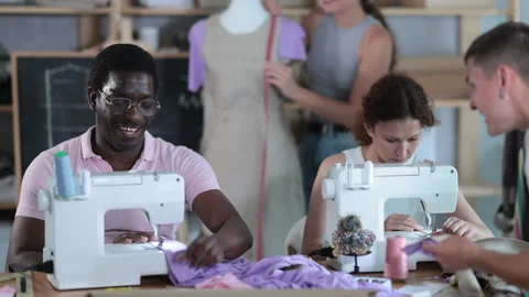 Multiethnic group of engaged fashion students of different ages sewing together Stock Footage 313879166