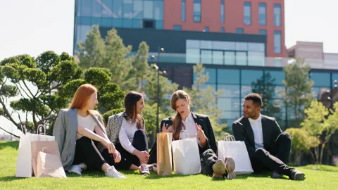 Multiethnic group of friends after a good shopping taking a sit down on the Video stock 164858879