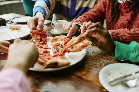 Multiethnic Group of Friends Sharing Pizza at Restaurant Table Stock Photos