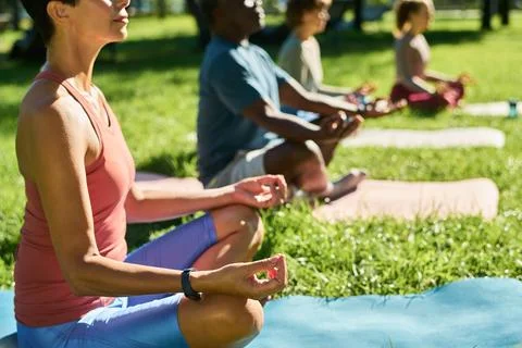 Multiethnic Group Meditating in Lotus Pose during Outdoor Yoga Class Foto stock