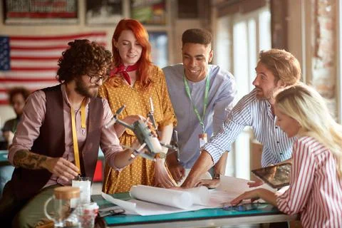 Multiethnic group of people analyzing drone according to their needs on paper Stock Photos