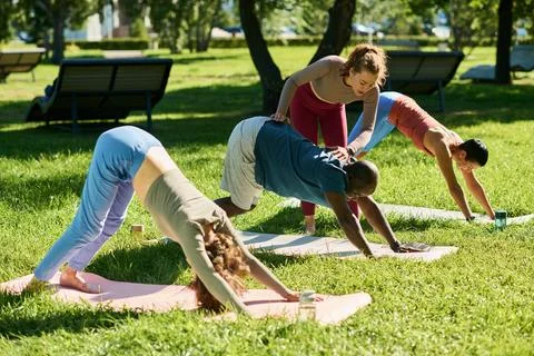Multiethnic Group Practicing Yoga with Instructor in Park Foto stock
