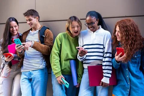Multiethnic group of students browsing mobile phone apps outdoors. Stock-Fotos
