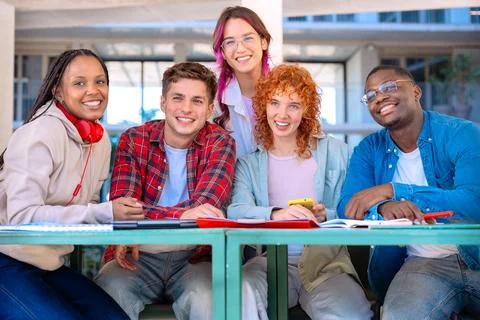 Multiethnic group of students laughing,browsing mobile phone apps outdoors. Stock Photos