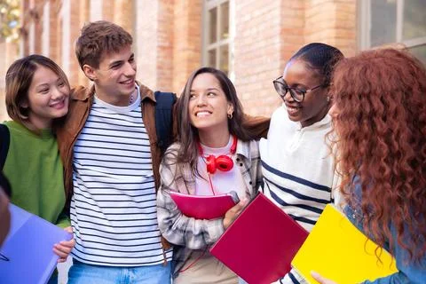Multiethnic group of students walking with notebooks, laughing. Stock Photos