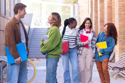 Multiethnic group of students walking with notebooks, laughing. Stock Photos