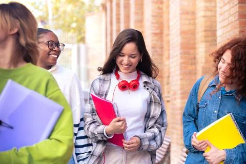 Multiethnic group of students walking with notebooks, laughing. Stock Photos