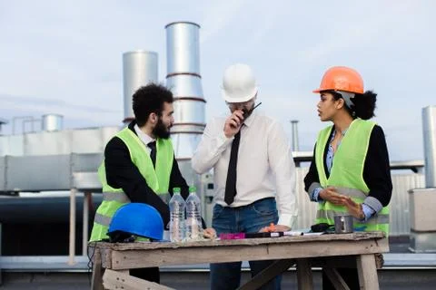 Multiethnic group of workers architect and two engineers have a conversation on Stock Photos