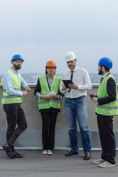 Multiethnic group of workers engineers architects foreman analyzing the plan of Stock Photos