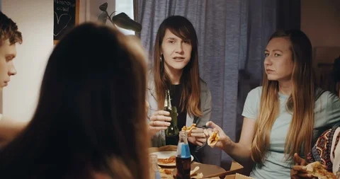 Multiethnic group of young men and women enjoying pizza and drinks, talk at a Stock Footage 116317305
