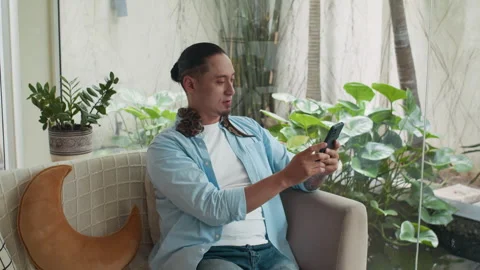 Multiethnic Guy Relaxing on Couch with Pet Snake on Neck, Videocalling on Phone Stock Footage 304541350