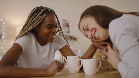 Multiethnic lesbian couple sitting at the table, talking, smiling and holding Stock Footage 146184363