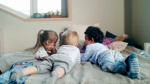 Multiethnic Little Kids Lying on Bed and Watching Cartoon on Tablet Stock Footage 101042386