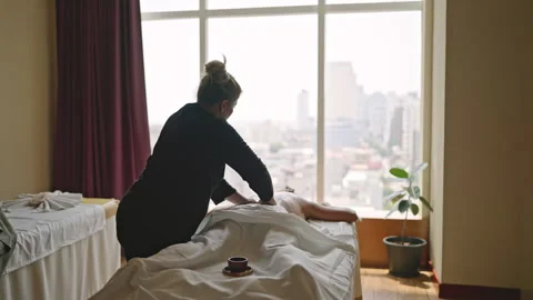 Multiethnic masseuse performs relaxing back massage to a young blonde causasian Stock Footage 252773709