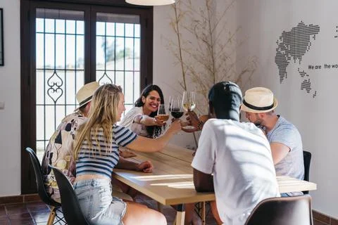 Multiethnic meeting toasts with wine while playing dice Stock Photos