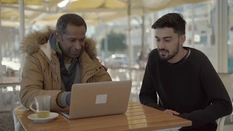 Multiethnic men talking and using laptop in cafe Stock Footage 102211936