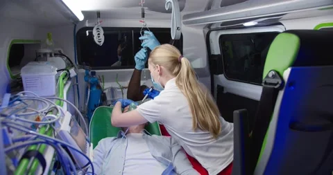 Multiethnic paramedics saving life of old man in ambulance. Medic giving oxygen Stock Footage 158308916