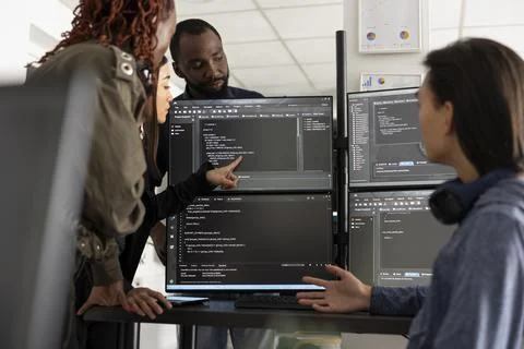 Multiethnic programmers analyzing code together at office desk 库存照片