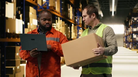 Multiethnic staff members sorting cardboard boxes in industrial storage facility Stock Footage 332909523