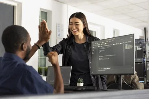Multiethnic team celebrating coding success with high five Stock Photos