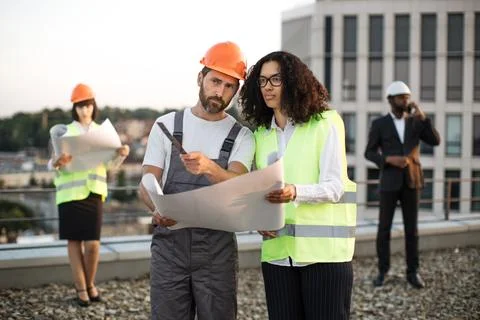 Multiethnic team of developers examining architectural plan 写真素材
