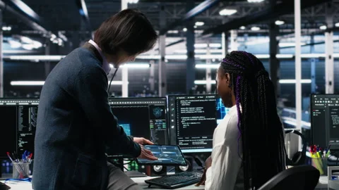 Multiethnic team in diverse data center coding with generative AI assistance Stock Footage 313639898