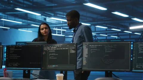 Multiethnic team of engineers in data center uses laptop to do programming Stock Footage 275999796