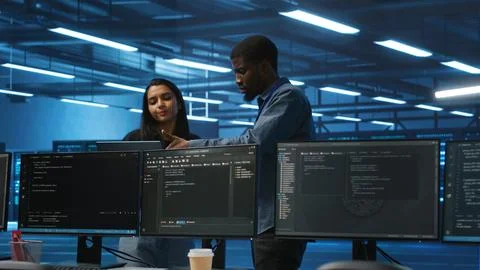 Multiethnic team of engineers in data center uses laptop to do programming 库存照片