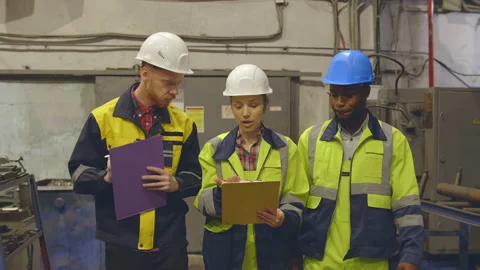 Multiethnic team of engineers discussing production using clipboards Stock Footage 131319273