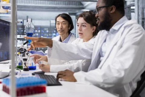 Multiethnic team in laboratory using computer program for DNA data analysis Stock Photos