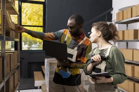 Multiethnic team using a scanner to check awb tags on stored goods Stock Photos