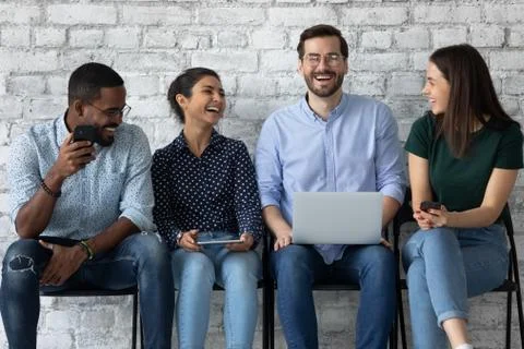 Multiethnic teammates spending time in queue sharing information by gadgets Stock Photos