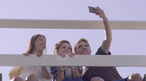 Multiethnic Teens Sit On Bridge And Take Selfies, They Make Silly Faces Video stock 57294270
