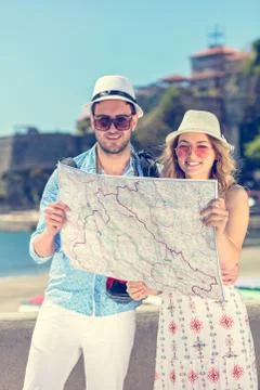 Multiethnic traveler couple using generic local map together on sunny day. Stock Photos