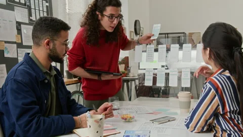 Multiethnic UI Designers Examining Wireframes at Project Team Meeting Stock Footage 327907128