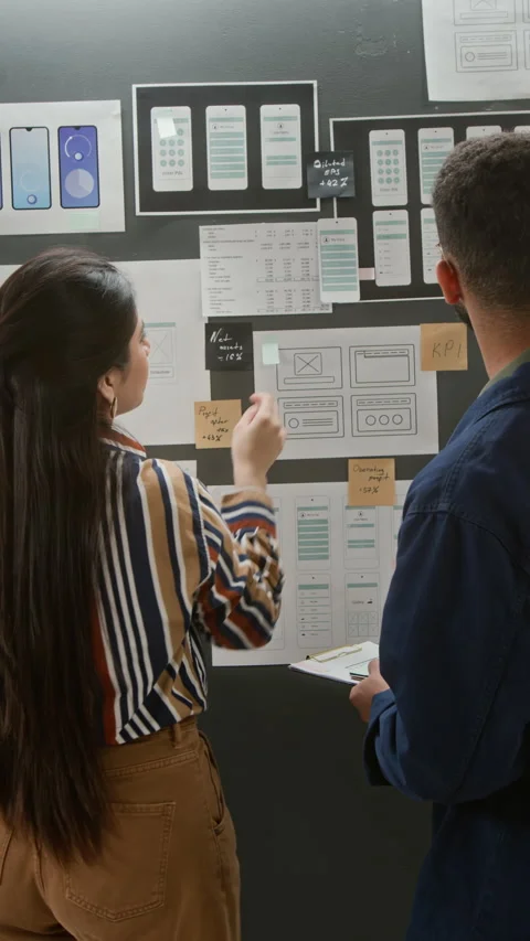 Multiethnic User Interface Developers Reviewing Wireframes on Wall Project Board Stock Footage 327907991