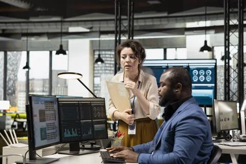 Multiethnic work team consulting each other in completing monthly reports Stock Photos